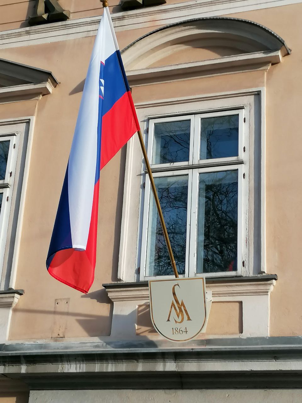 Slovenska zastava na zgodovinski stavbi s ploščico 1864